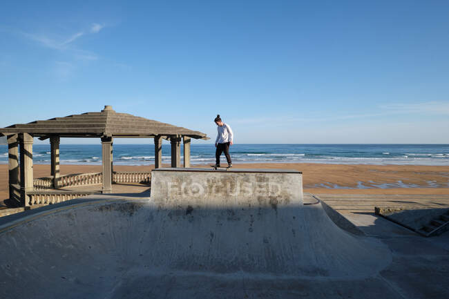 Irriconoscibile teen boy a cavallo skateboard in skate park nella giornata di sole in riva al mare — Foto stock
