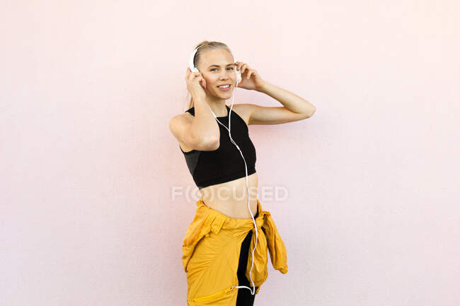 Jovem caucasiana vestindo fones de ouvido e roupas esportivas e ouvir música — Fotografia de Stock