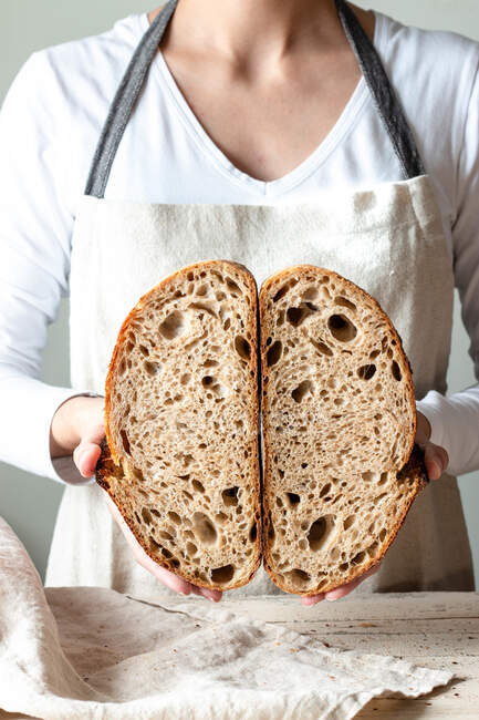 Crop faceless woman hands holding freshly baked sourdough rye bread Crumb white cutting in half — Stock Photo