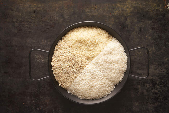 From above of bowl with assorted types of dried rice on black background — Stock Photo