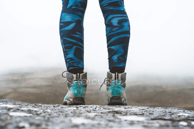 Recorte de algunas piernas de excursionista anónimo con un fondo de niebla entre las montañas - foto de stock