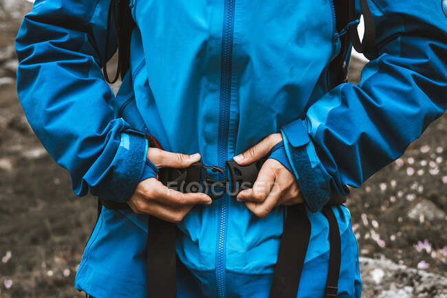 Обрізати жінку, що подорожує в зручній синій куртці і кріпиться рюкзак кнопка — стокове фото