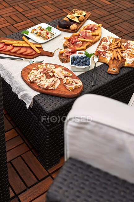 Mesa montada em um terraço com vários aperitivos deliciosos, como presunto serrano, espetado em conserva, nozes, etc — Fotografia de Stock