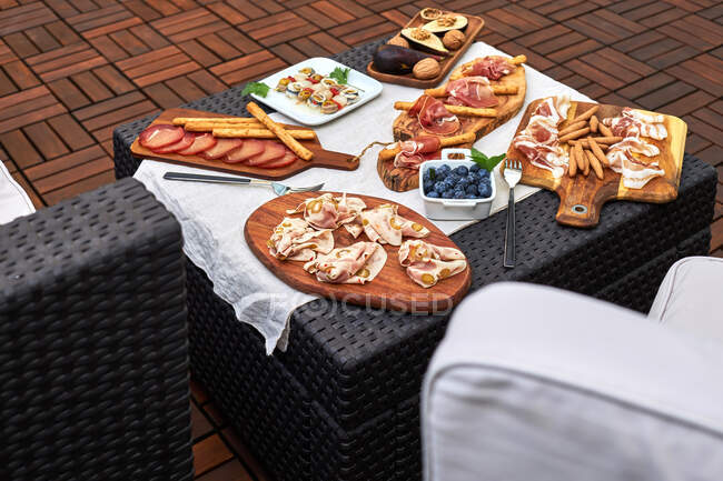 Mesa montada en una terraza con varios aperitivos deliciosos como jamón serrano, pinchos en escabeche, nueces, etc. - foto de stock