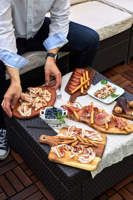 З понад врожаю анонімні чоловіки сидять за столом з різними смачними закусками на терасі. — стокове фото