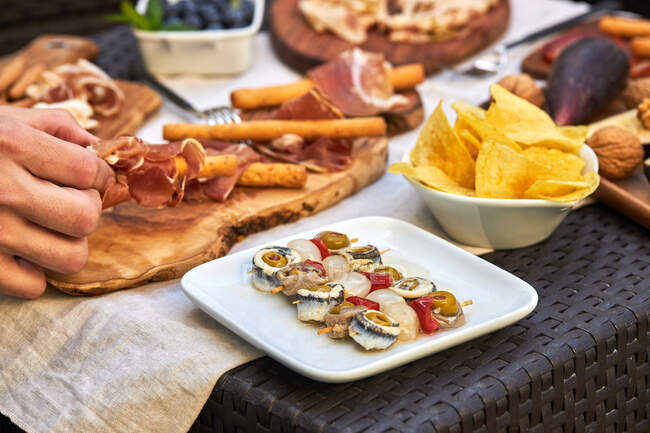 Angolo alto di deliziose verdure sottaceto spiedate con sardine, peperoncino alle olive e cipolla posta sul tavolo con assortimento di snack — Foto stock