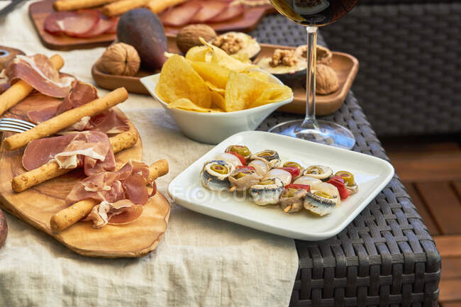 Vista superior del apetecible surtido de antipasto servido con platos en la mesa en la terraza - foto de stock