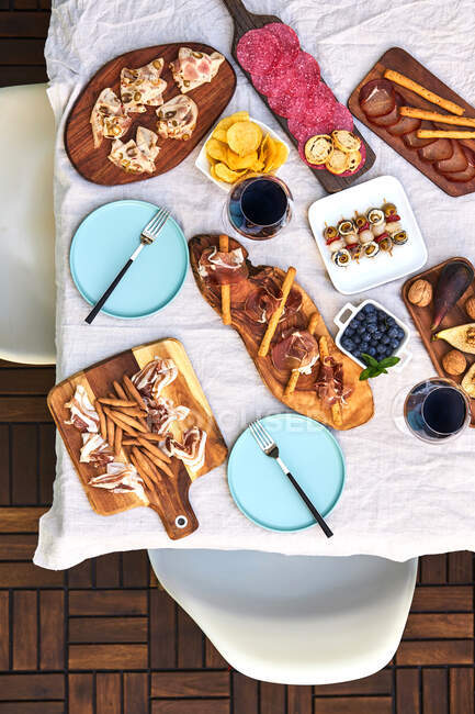 Draufsicht auf das appetitliche Antipastosortiment, serviert mit Tellern auf dem Tisch auf der Terrasse — Stockfoto
