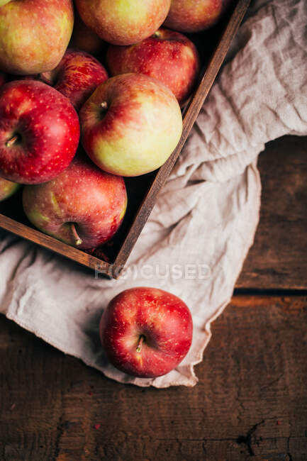 Свежие красные яблоки в коробке на столе — стоковое фото