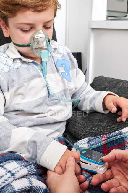 Crop unrecognizable woman using modern pulse oximeter on finger of kid for measuring oxygen level in blood — Stock Photo