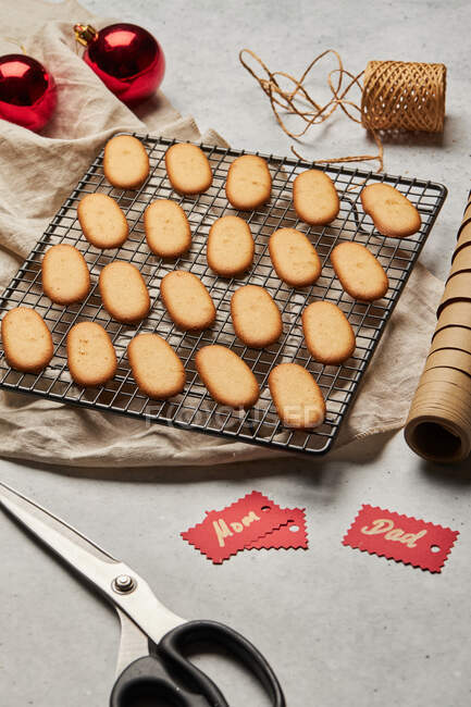 From above of tasty Christmas biscuits placed on metal baking net on table with assorted wrapping supplies — Stock Photo