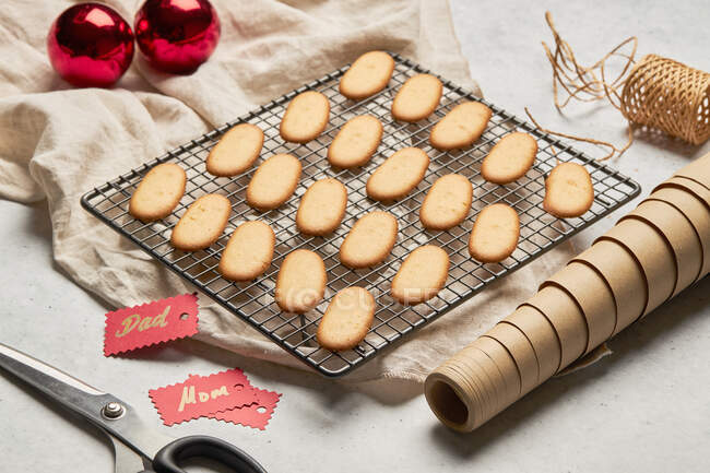 Desde arriba de sabrosas galletas de Navidad colocadas en la red de cocción de metal en la mesa con surtidos suministros de envoltura - foto de stock
