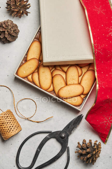 From above of tasty Christmas biscuits placed on box on table with assorted wrapping supplies — Stock Photo