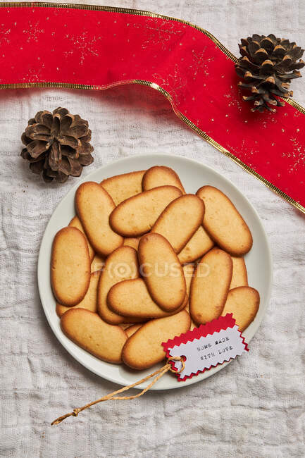 Vista superior de la pila de deliciosas galletas de Navidad colocadas en el plato en mantel para la celebración de las fiestas - foto de stock