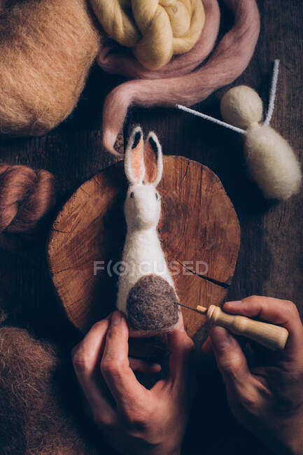 Сделав вручную пасхального кролика из шерсти и войлока на темном деревянном столе — стоковое фото