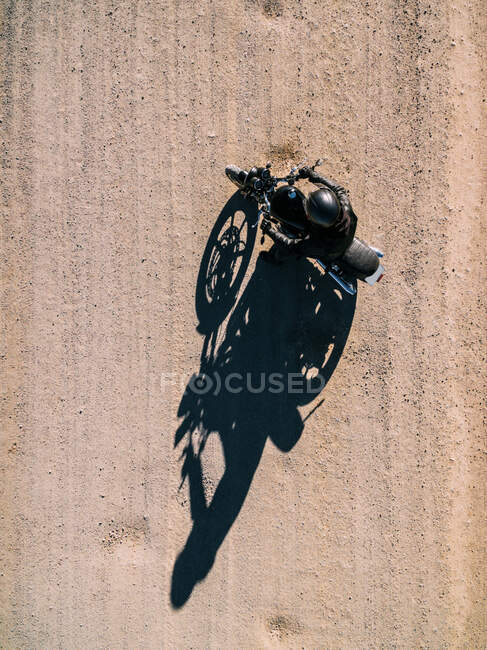 Сверху вид с воздуха на человека за рулем мотоцикла по сельской дороге при солнечном свете в сельской местности — стоковое фото