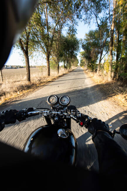 Vue arrière de la moto de course rapide sans visage à travers la forêt en milieu rural — Photo de stock