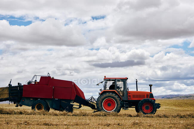 Сушений сінокоток і сучасний трактор розмістили на сільськогосподарському полі в гірській місцевості влітку — стокове фото