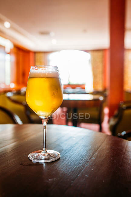 Verre de bière dans une table en bois dans un pub sur fond flou — Photo de stock