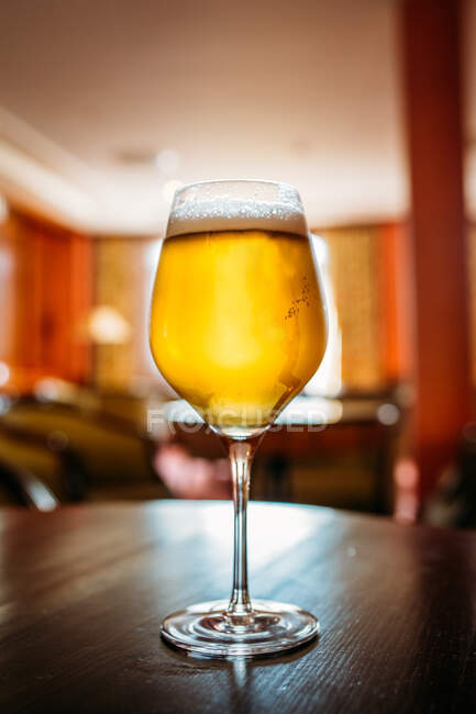 Verre de bière dans une table en bois dans un pub sur fond flou — Photo de stock