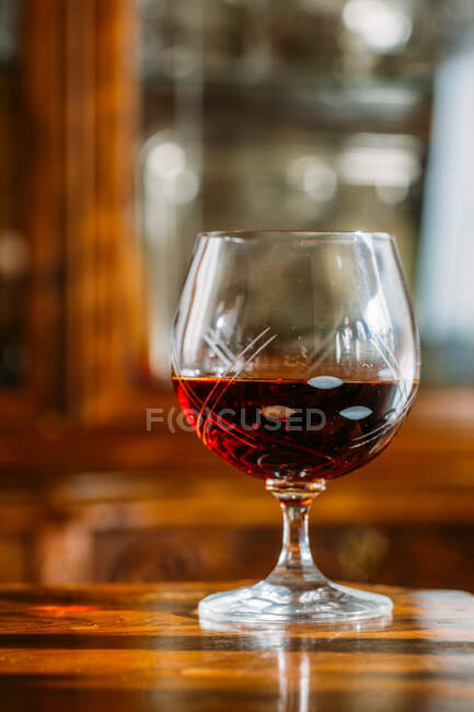 Old fashioned cognac glass on wooden table with natural light — Stock Photo