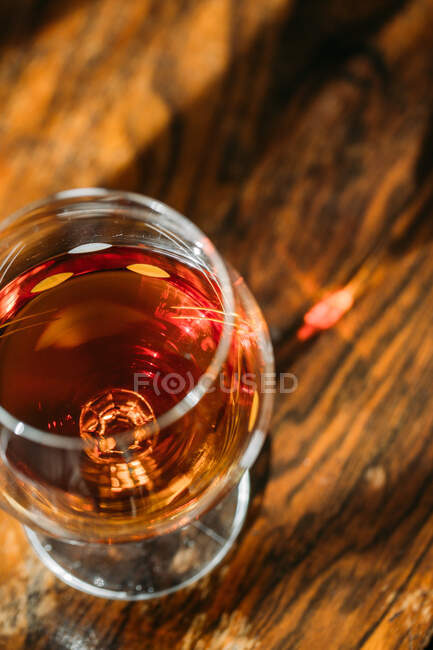 Old fashioned cognac glass on wooden table with natural light — Stock Photo