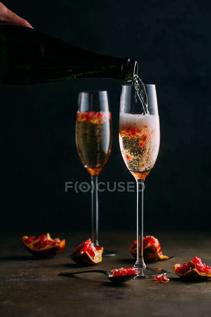 Cosecha mano que sirve cóctel de champán con granada - foto de stock