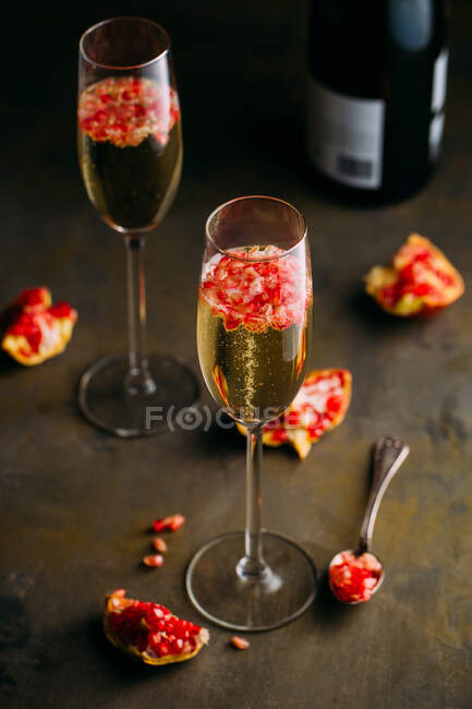 Composição de natureza morta de coquetel de champanhe com romã em uma superfície rústica — Fotografia de Stock