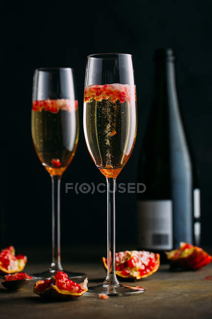 Champagne cocktail with pomegranate placed on rustic surface against dark background — Stock Photo