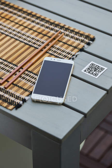 From above of mobile phone placed on table with QR code of restaurant menu — Stock Photo