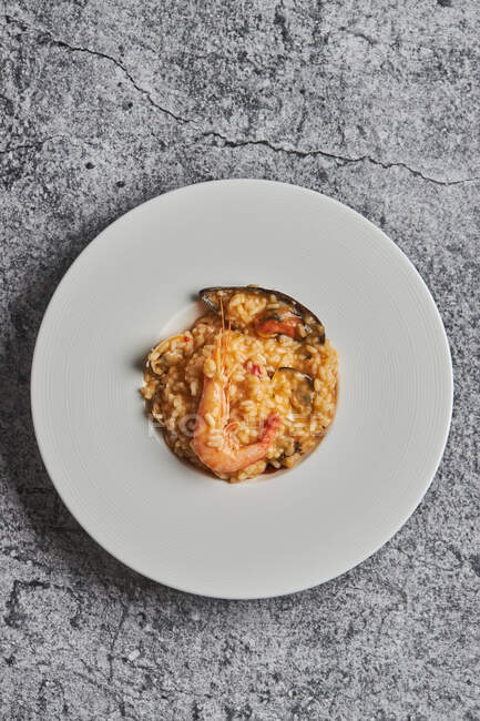 Dall'alto di riso appetitoso con frutti di mare assortiti serviti sul piatto sul tavolo nel ristorante — Foto stock
