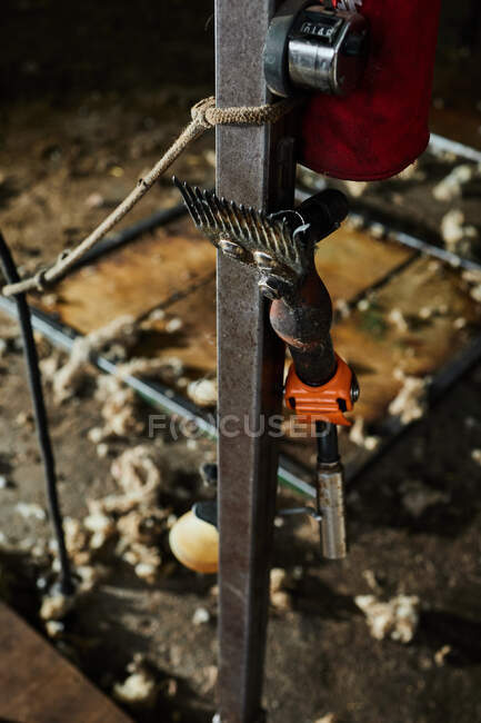 Cortadores de metal enferrujado para tosquiar ovelhas penduradas perto de feixe de metal no celeiro no campo — Fotografia de Stock