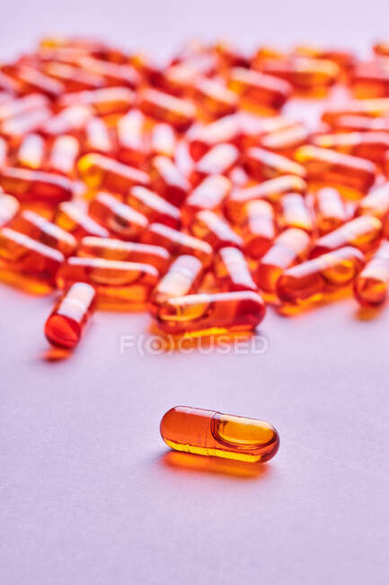 Zusammensetzung orangefarbener Pillen auf rosa Hintergrund im Lichtstudio verstreut — Stockfoto