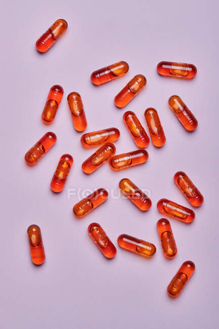 Vista dall'alto composizione di pillole arancioni sparsi su sfondo rosa in studio luce — Foto stock