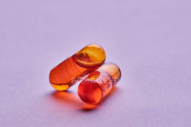 Composition of orange pills on pink background in light studio — Stock Photo