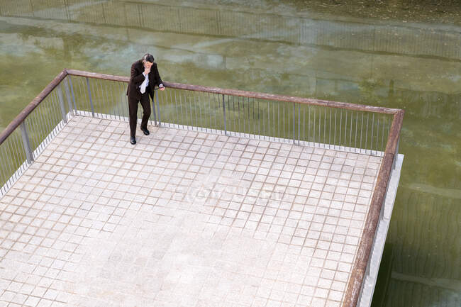 Desde arriba de hombre barbudo de mediana edad en traje elegante navegando en la tableta en la terraza - foto de stock