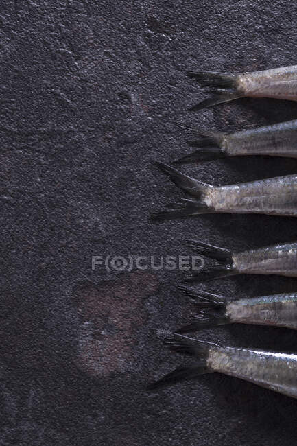 Nahaufnahme von rohen Sardellenschwänzen, die auf dunkler Oberfläche liegen — Stockfoto
