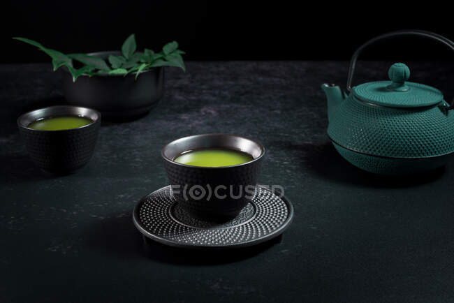 Schwarze Keramiktasse mit traditionellem grünen japanischen Matcha-Tee, serviert auf dem Tisch mit Teekanne — Stockfoto
