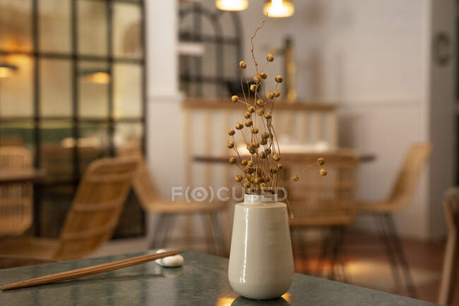 Vase en céramique avec des plantes séchées placées sur la table dans un restaurant asiatique à l'intérieur confortable — Photo de stock