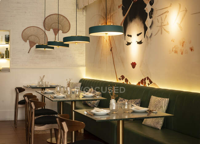 Уютный интерьер азиатского ресторана с удобным диваном и стеклянными столами с посудой — стоковое фото