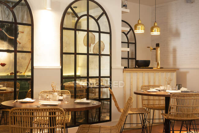 Mesas de madera y sillas de mimbre colocadas en acogedor restaurante espacioso con interior moderno - foto de stock