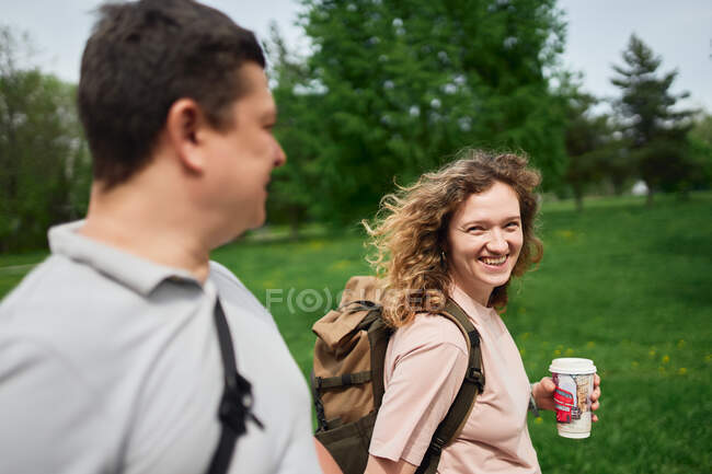 Вид сбоку пары, наслаждающейся прогулкой вместе в пышном парке в летний день — стоковое фото