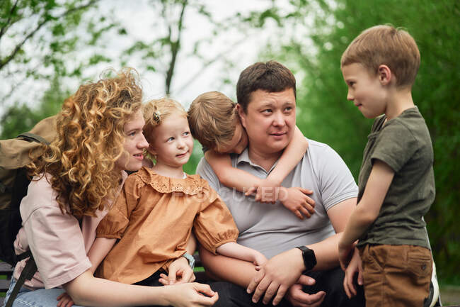 Content parents and cute kids enjoying summer weekend and spending time together in green park — Stock Photo