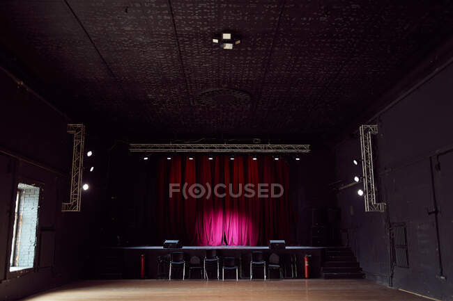 Interior de sala de conciertos vacía sin sillas y pequeño escenario con cortinas púrpuras - foto de stock