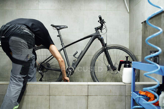 Неузнаваемая кассета мужской механической чистки велосипедного колеса с водой в мастерской — стоковое фото