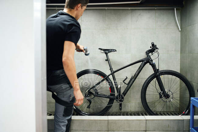 Cassetta di pulizia meccanica maschio della ruota della bicicletta con spazzola in officina — Foto stock