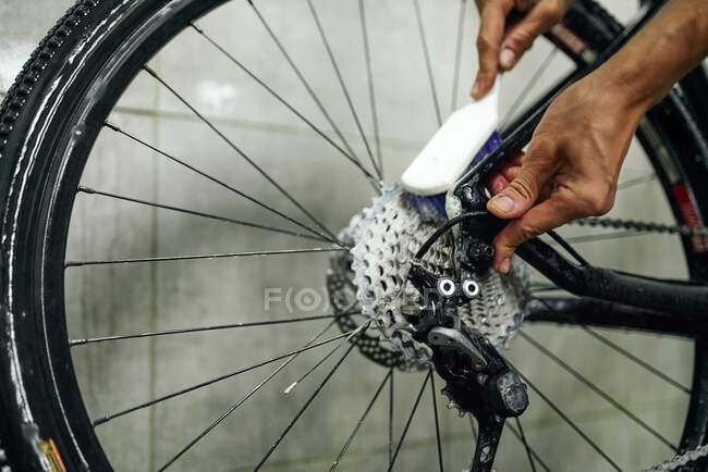 Неузнаваемая кассета для механической чистки мужского пола велосипедного колеса с щеткой в мастерской — стоковое фото