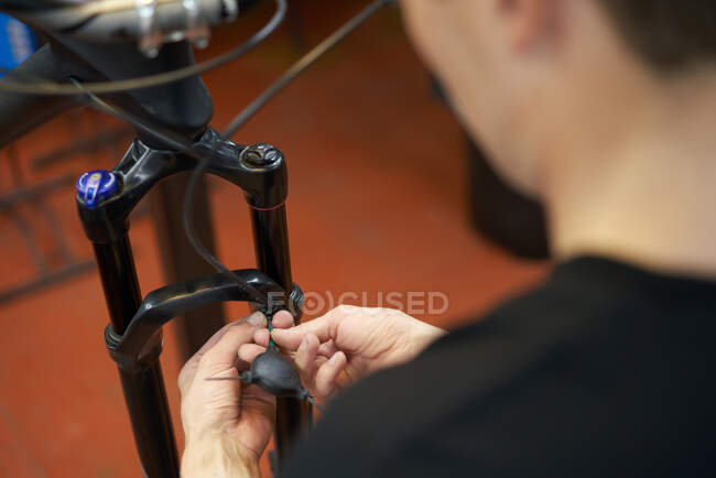 Dall'alto di coltura anonima maschio meccanico riparazione cavo freno della bici in officina — Foto stock
