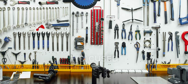 Kit of various professional repair instruments hanging on wall near workbench in garage — Stock Photo