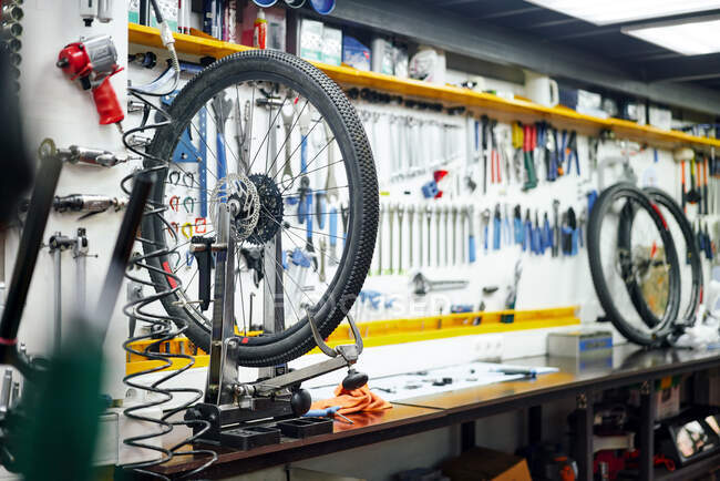 Bicicletta moderna attaccata al rack vicino alla parete con strumenti assortiti in officina moderna — Foto stock